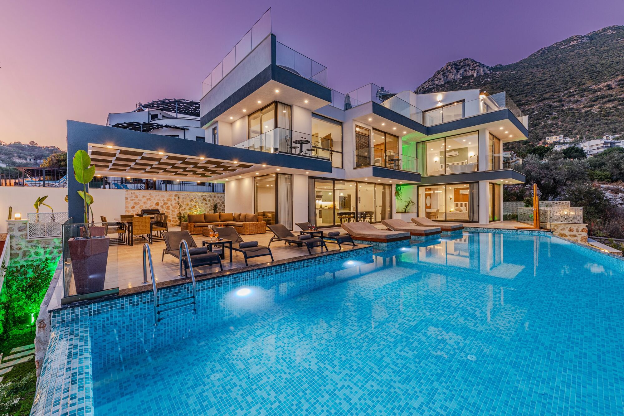 A modern hillside villa and infinity pool at sunset, built complete