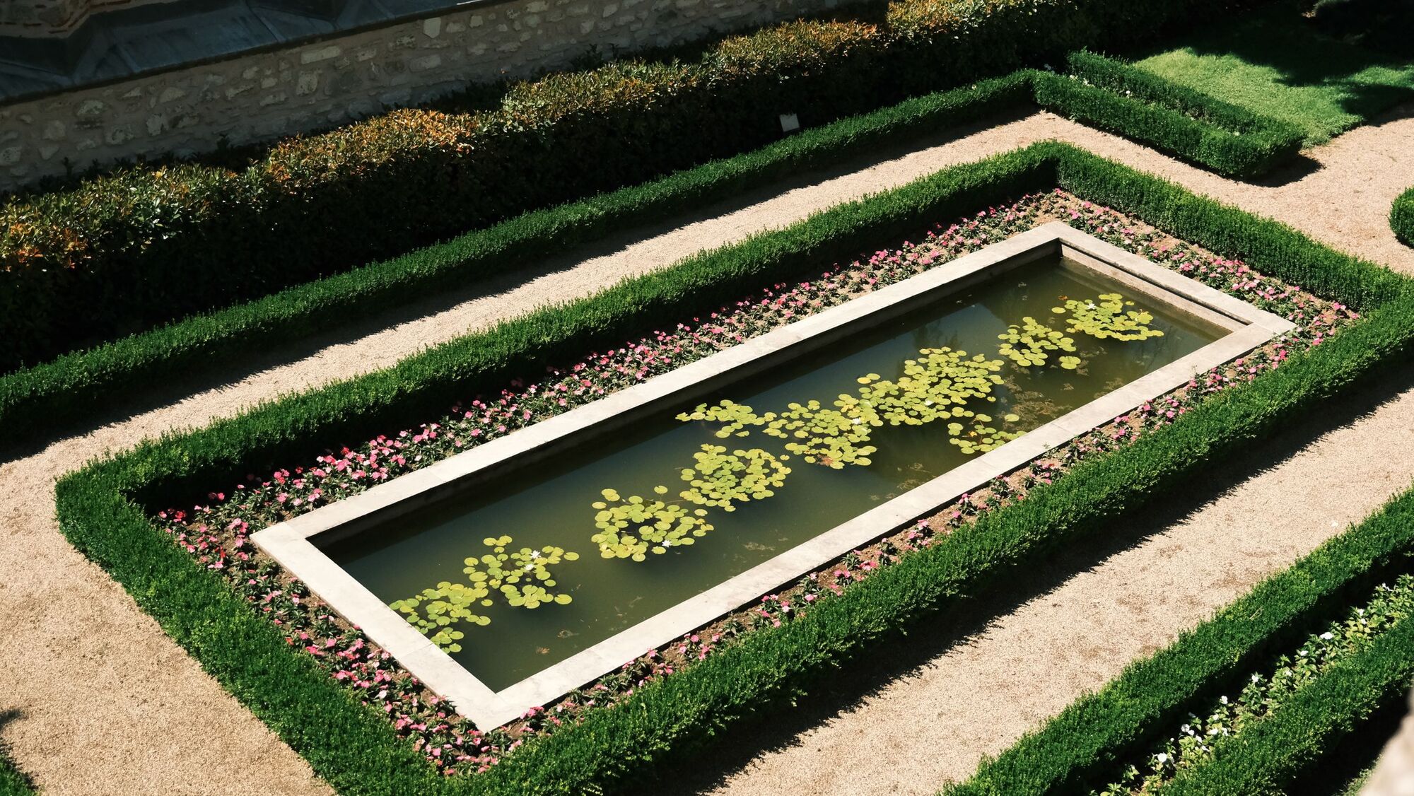 Overhead view of a formal garden with clipped hedges and a water feature