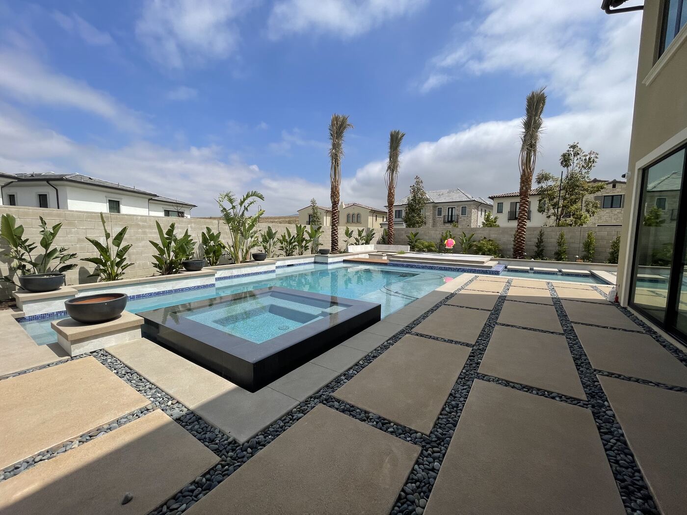 Pool with wooden deck, two-story home beyond