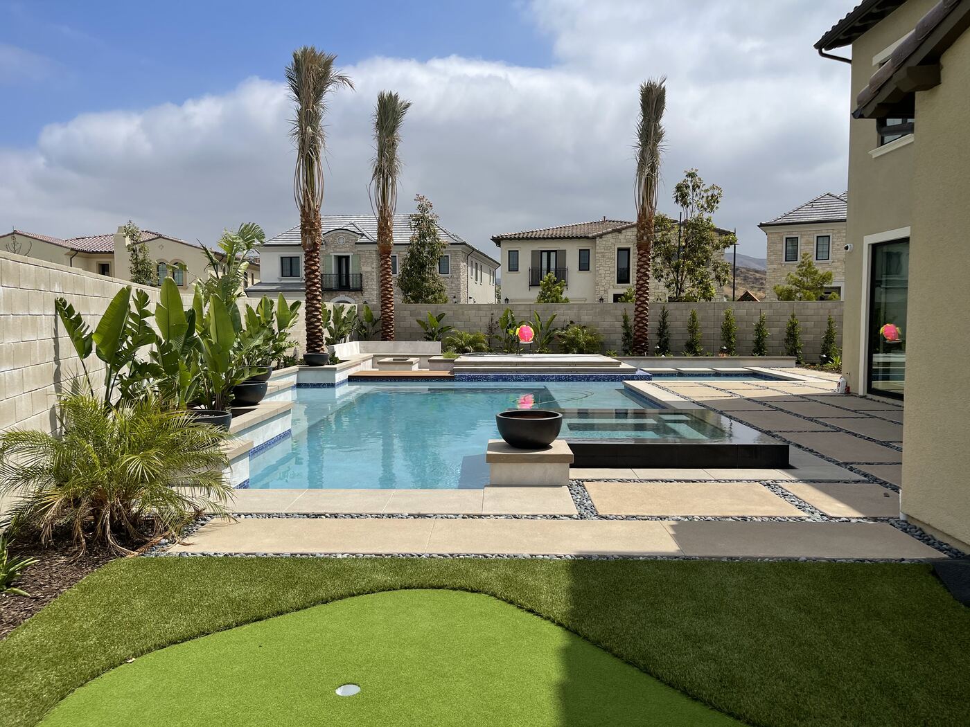 Raised spa spilling into pool beside palms