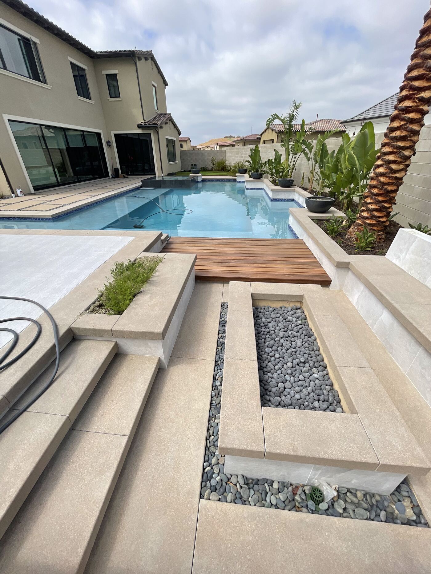 Geometric pool with wood bridge and pebble beds