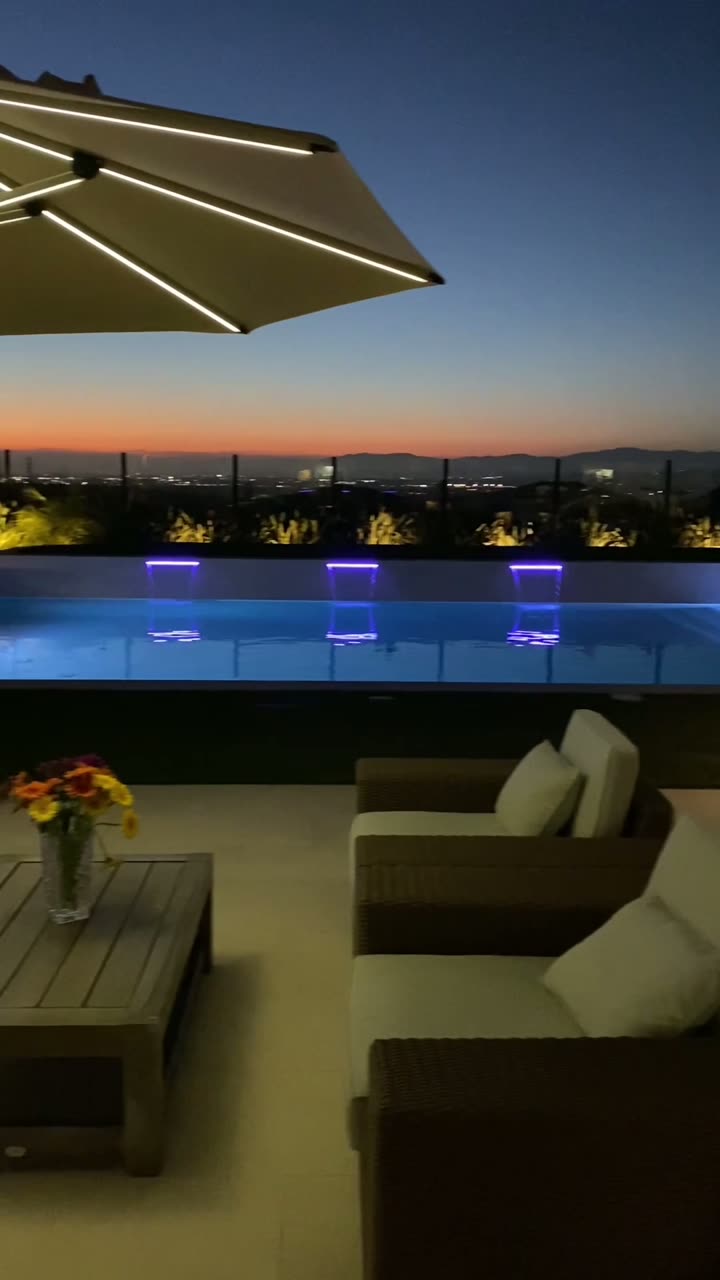 Hillside pool with lit fire pots under a pergola